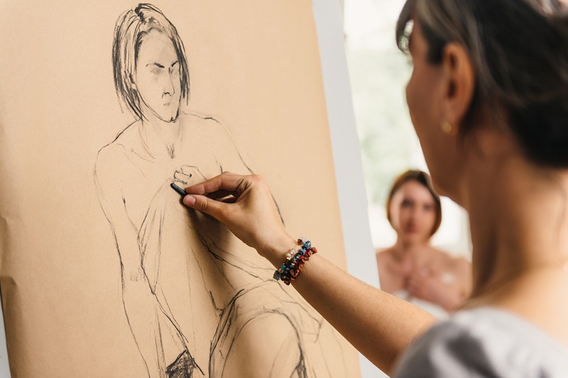 A person drawing using charcoal